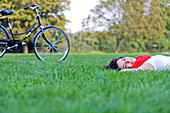 Woman with bicycle lying down in the park
