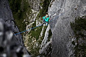 Junger Mann balanciert über eine Highline zwischen zwei Felsen, Oberammergau, Bayern, Deutschland, Europa