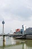 Boot mit Deutschlandfahne im Medienhafen mit Fernsehturm und Häusern des Architekten Frank Gehry, Düsseldorf, Nordrhein-Westfalen, Deutschland, Europa