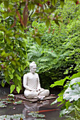Buddha in einem Teich mit Seerosen und Kois im Garten von Andre Heller, Giardino Botanico, Gardone Riviera, Gardasee, Lombardei, Italien, Europa