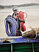 Old Tamil fisherman carrying ropes back to the boat, Uppuveli, Tamil province, Sri Lanka, Indian Ocean