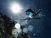 Female skier jumping over rock