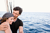 couple standing at rail of sailing boat