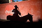 The shadow of a picador on his horse is cast on a door with a Coca-Cola logo before a bullfight in Tlaxcala, Mexico.