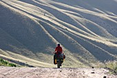 Female cyclist on a mountain road, Kyrgyzstan