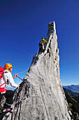 Young woman belaying climber at pinnacle, Kampenwand, Chiemgau Alps, Chiemgau, Upper Bavaria, Bavaria, Germany