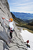 Young woman climbing while young man belaying, Multerkarwand, Treffauer, Wegscheidalm, Wilder Kaiser, Kaiser Mountain Range, Tyrol, Austria