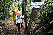 Junge Frau und junger Mann steigen durch Wald zum Klettersteig Rino Pisetta auf, Lago die Toblino, Sarche, Calavino, Trentino, Trentino-Südtirol, Italien