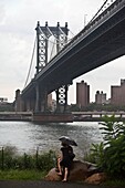 New York - United States, People gazing the skyline of Manhattan and the East river, in Brooklyn bridge park, under the Manhattan bridge