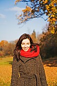 Portrait of a brunette woman in park in Autumn smiling at camera