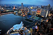 Asia, Southeast Asia, Singapore, people gazing the city from the terrace of the Marina Bay Sands Resort at night