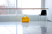 Hospital corridor. Smooth shiny floor. Chair. Glass window with view to the outdoors. Large yellow bag with handles placed on the floor., Tartu University  Hospital, Estonia