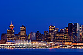 The Vancouver skyline at twilight or dawn, with low light and blue sky, and flat calm water. Lit up skyline and tall buildings. British Columbia, Canada., Vancouver Skyline