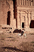 Beduin woman riding donkey in front of Royal Tomb, Petra, UNESCO world heritage, Wadi Musa, Jordan, Middle East, Asia