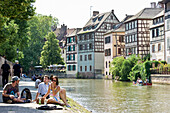 People sitting along the bank of the river, Petite France quarter, Strasbourg, Alsace, France