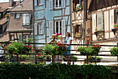 Mother and two daughters standing on a bridge in front of half-timbered houses in Petite Venise, Colmar, Alsace, France