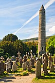 Round tower and gravestones at the historic site of Glendalough, County Wicklow, Ireland, Europe