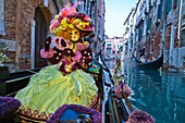 A masked woman in a gondola at the carnival in Venice, Italy, Europe