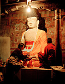 Restorers painting buddha statue in prayers room of convent Tiksey Gonpa, southeast of Leh, Ladakh, Jammu and Kashmir, India