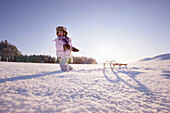 Girl pulling a sledge, Hoehenberg, Muensing, Bavaria, Germany