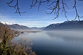 Foggy lake in the alps with snow on tops of the mountains and a misty sunny day