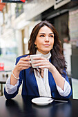 Portrait of a pretty brunette woman having a coffee outdoor smiling