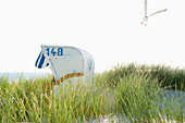 White beachchair with sea gull in sand dunes, sandbank, Nebel, Amrum, North Frisian Islands, Schleswig-Holstein, Germany