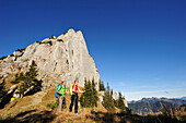 Young couple mountain hiking at moung Risserkogel, Plankenstein in background, Bavarian Prealps, Mangfall Mountains, Bavaria, Germany