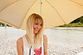Young woman with a sunshade on Isar riverbank, Munich, Bavaria, Germany
