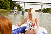 Young people with a rubber dinghy at the Isar river, Munich, Bavaria, Germany