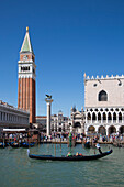 Gondoliere rudert Gondel mit Touristen entlang San Marco Basin vor Campanile di San Marco Turm und Dogenpalast am Markusplatz, Venedig, Venetien, Italien, Europa