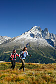 Frau und Mann beim Wandern mit Blick auf Aiguille Verte und Grand Dru, Mont Blanc-Gruppe, Mont Blanc, Chamonix, Savoyen, Frankreich