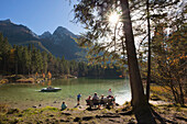 Familie sitzt auf einer Bank am Ufer des Hintersees, Blick auf den Hochkalter, Ramsau, Berchtesgadener Land, Nationalpark Berchtesgaden, Oberbayern, Bayern, Deutschland, Europa