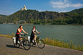 Zwei Radfahrerinnen vor der Marksburg, Unesco Weltkulturerbe, bei Braubach, Rhein, Rheinland-Pfalz, Deutschland