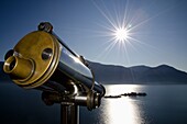 Watching with a telescope brissago islands on an alpine lake maggiore with mountains and sunbeam in switzerland