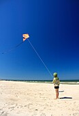 5 year old boy flying his kite on a beach