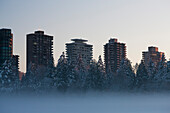 Fog on Lake With Snowy Trees and Tall Buildings in Background, Vancouver, Canada