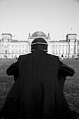 Man in Striped Suit and Hat, Rear View, Sitting in Front of Reichstag Building, Berlin, Germany