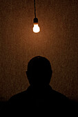 Man Sitting Under Light Bulb, Silhouette