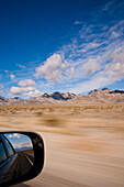A car driving through the desert landscape, Reflection of the landscape in the car wing mirror