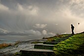 Person Standing On Cliff Overlooking Stormy Sea