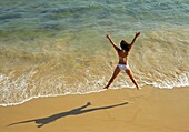 Woman Jumping For Joy On Beach