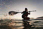 A Woman Paddling While On Her Knees On A Surf Board Off Dos Mares Beach, Tarifa, Cadiz, Andalusia, Spain
