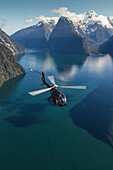Aerial view of Milford Sound with helicopter below, Mitre Peak, Fiordland National Park, South Island, New Zealand