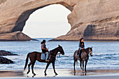Horse ride along Wharariki beach near Farewell Spit, Archway Islands in the background, South Island, New Zealand