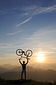 Mann hält Rennrad über Kopf, Kraftalm, Hohe Salve, Kitzbuehler Alpen, Tirol, Oesterreich