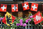 Bauernhof mit Schweizer Kreuz-Flaggen, Gstaad, Saanenland, Berner Oberland, Schweiz, Europa