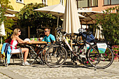 Paar auf Elektrorädern pausiert mit Apfelstrudel und Cappucino, Suedtirol, Italien