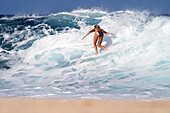 Hawaii, Oahu, North Shore, Surfer girl catching a wave.