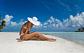 French Polynesia, Tuamotu Islands, Rangiroa Atoll, Woman sitting on white sand beach.